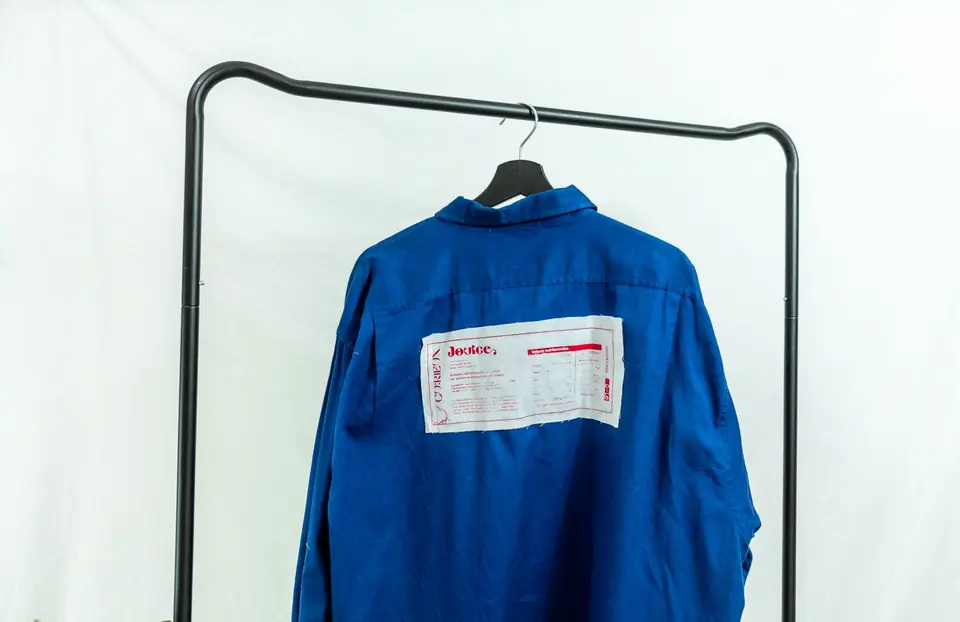 Camisa de trabajo azul con identificación colgada en una percha