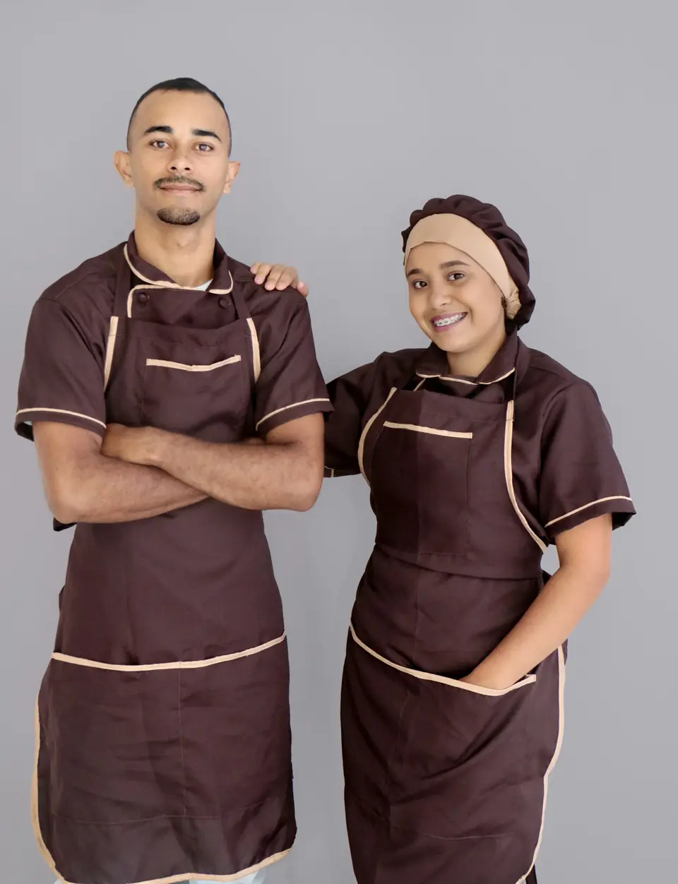 Dos profesionales de hostelería con delantales y uniforme a juego