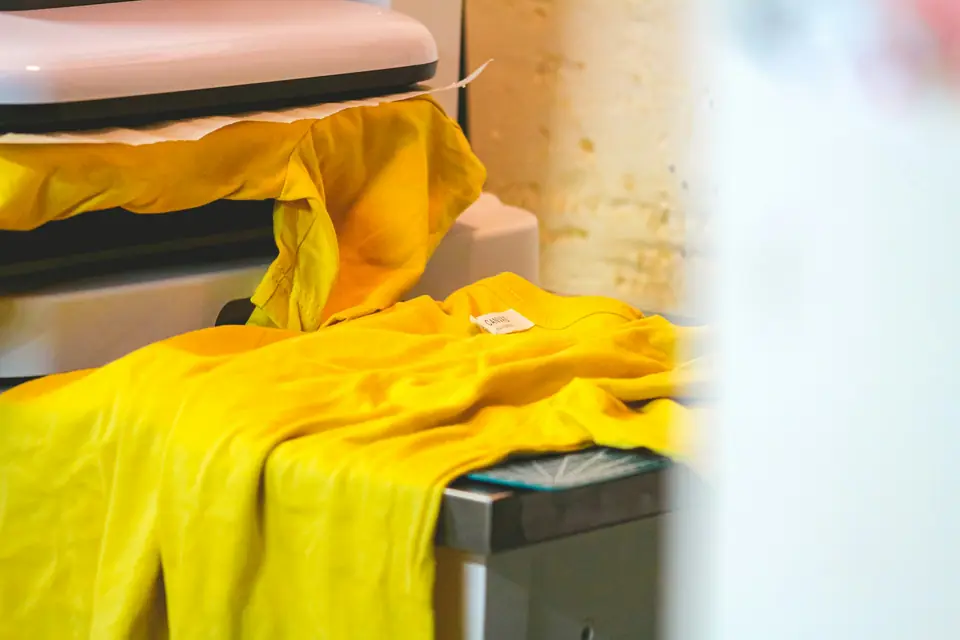 Camiseta amarilla en una plancha térmica durante la aplicación de un transfer